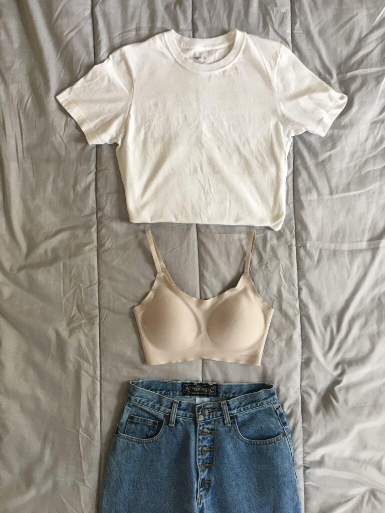 Neiwai barely zero bra in the color almond laid out next to a plain white t-shirt and a pair of vintage Paris Sports club mom jeans. 