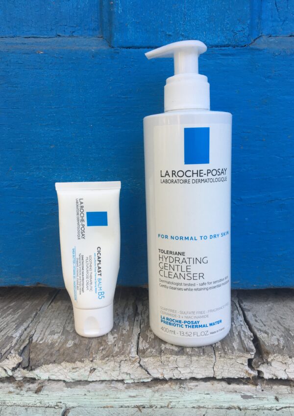 La Roche Posay Toleriane Cleanser and Cicaplast Balm B5 sitting on an old porch with a blue door behind it.