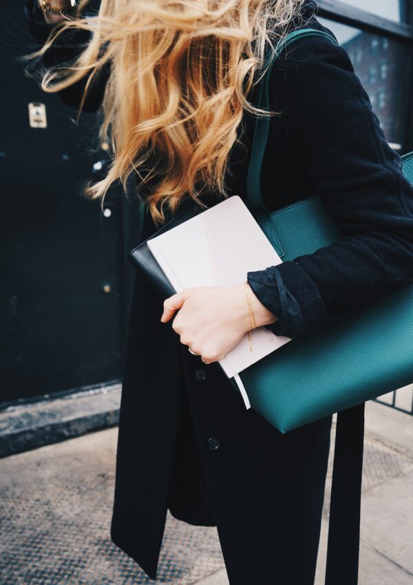 Girl holding a book outside with blonde hair blowing.