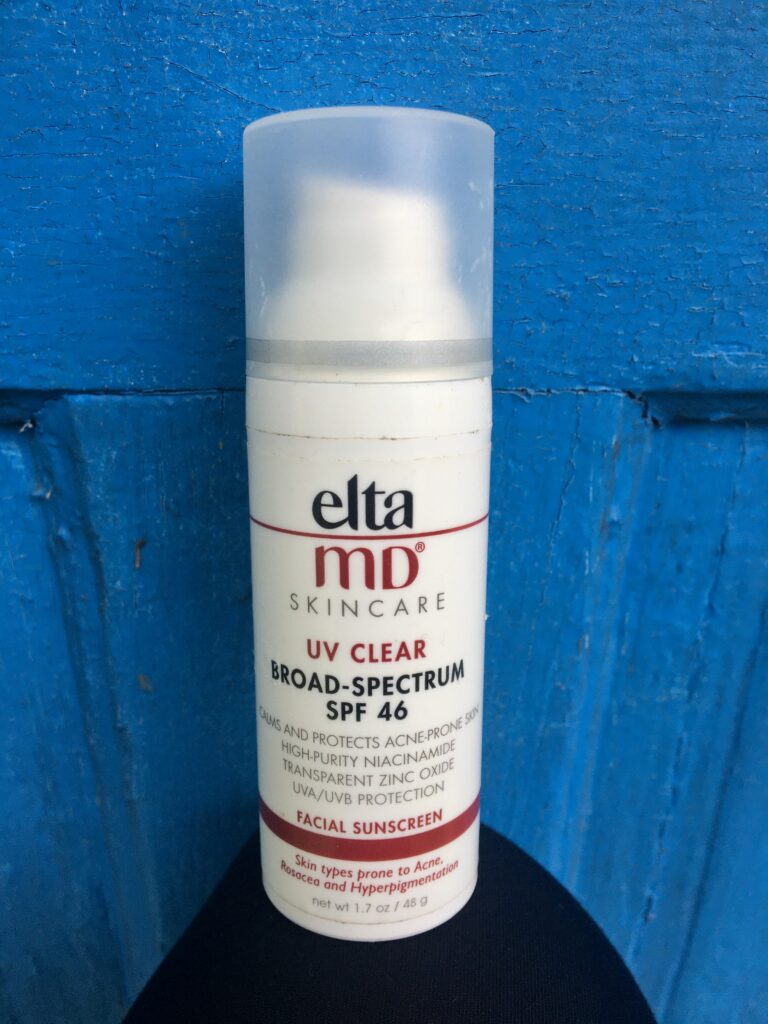 EltaMD Sunscreen sitting on top of a girls knee behind a bright blue background. 