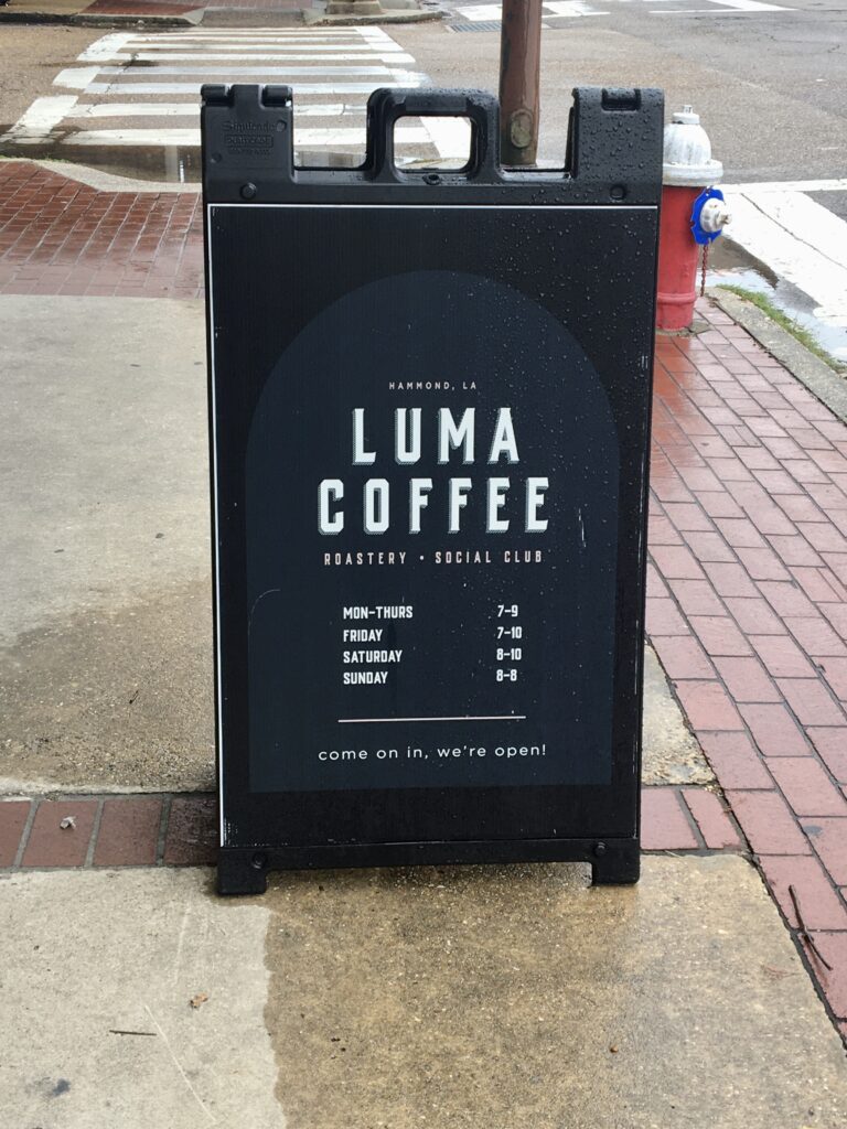 Luma Coffee hours sign outside of the shop during a rainy day. 