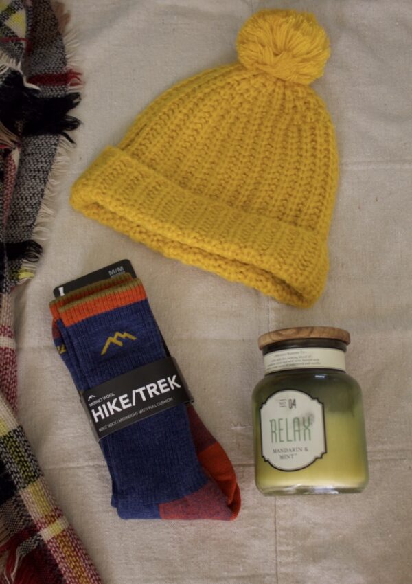 Darn Tough sock laying on a background with a candle and a yellow beanie hat.