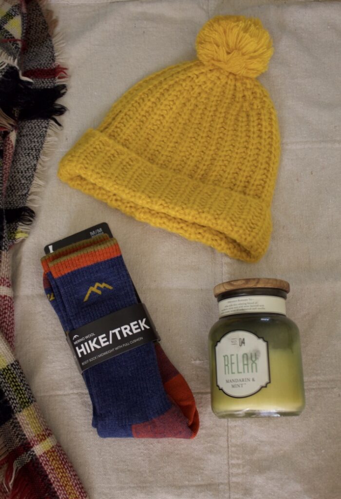 Darn Tough sock laying on a background with a candle and a yellow beanie hat. 