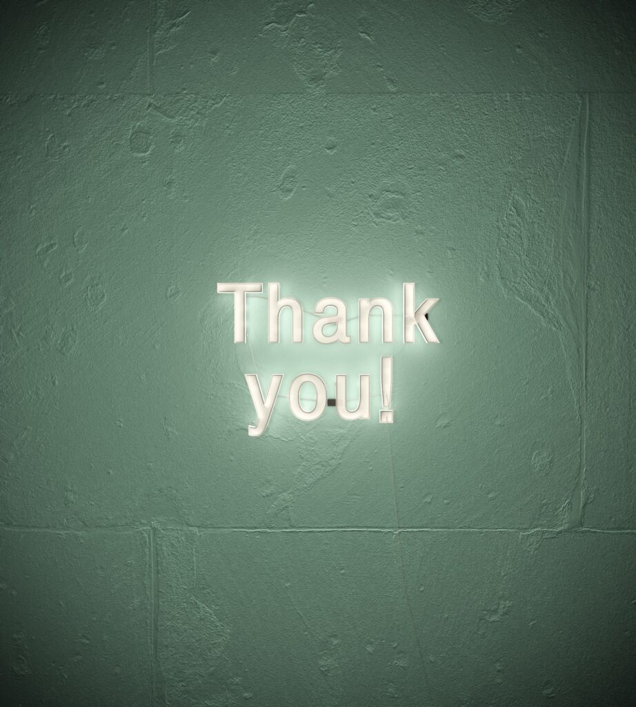 Green concrete wall with a fluorescent light that says thank you! Things to be thankful for picture. 