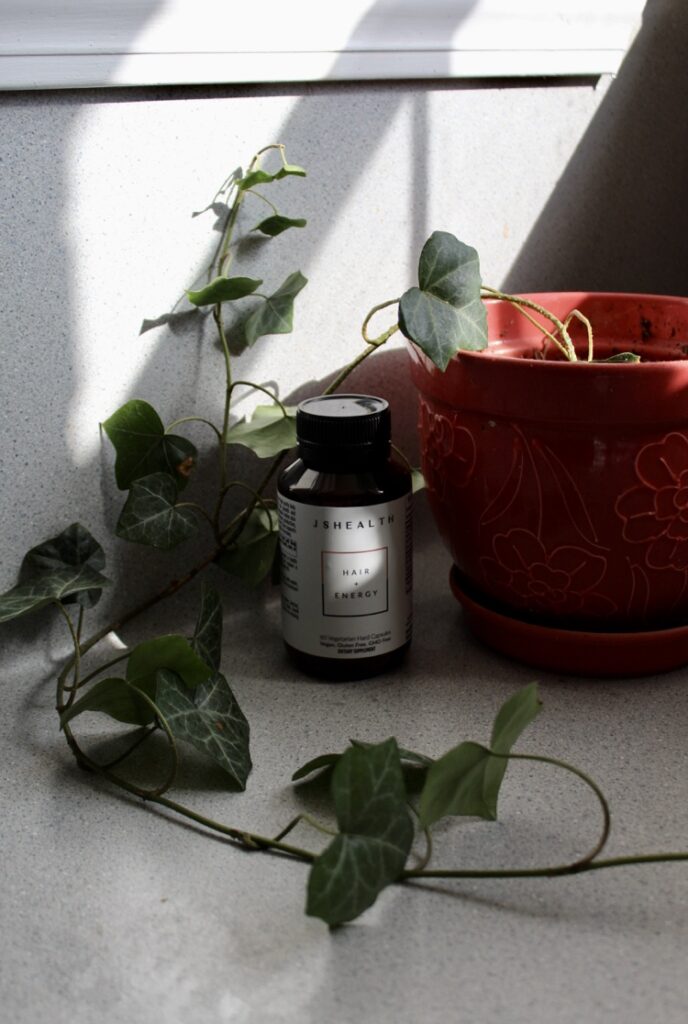 JSHealth Hair and Energy sitting in a window with the afternoon light and a plant. 