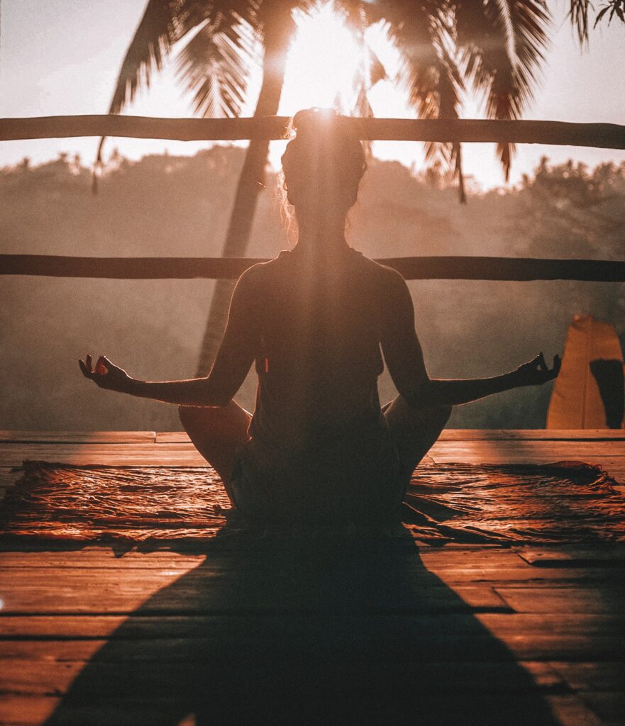 woman meditating on the porch in the tropics somewhere. Sunrise is happening. 