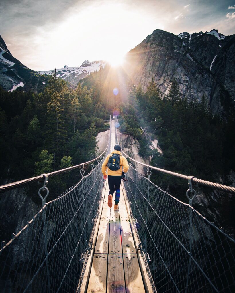 A man running on a rope bridge with a backpack on. 