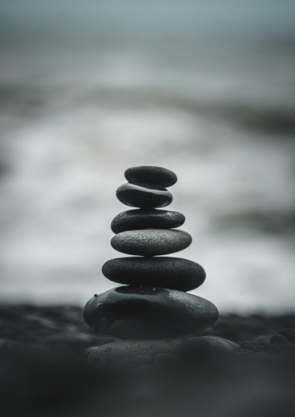 A stack of smooth gray rocks on top of each other with water in the back ground.