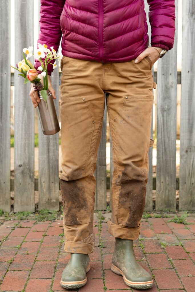 A guy with a vase of flowers and dirty Carhartt pants. 
