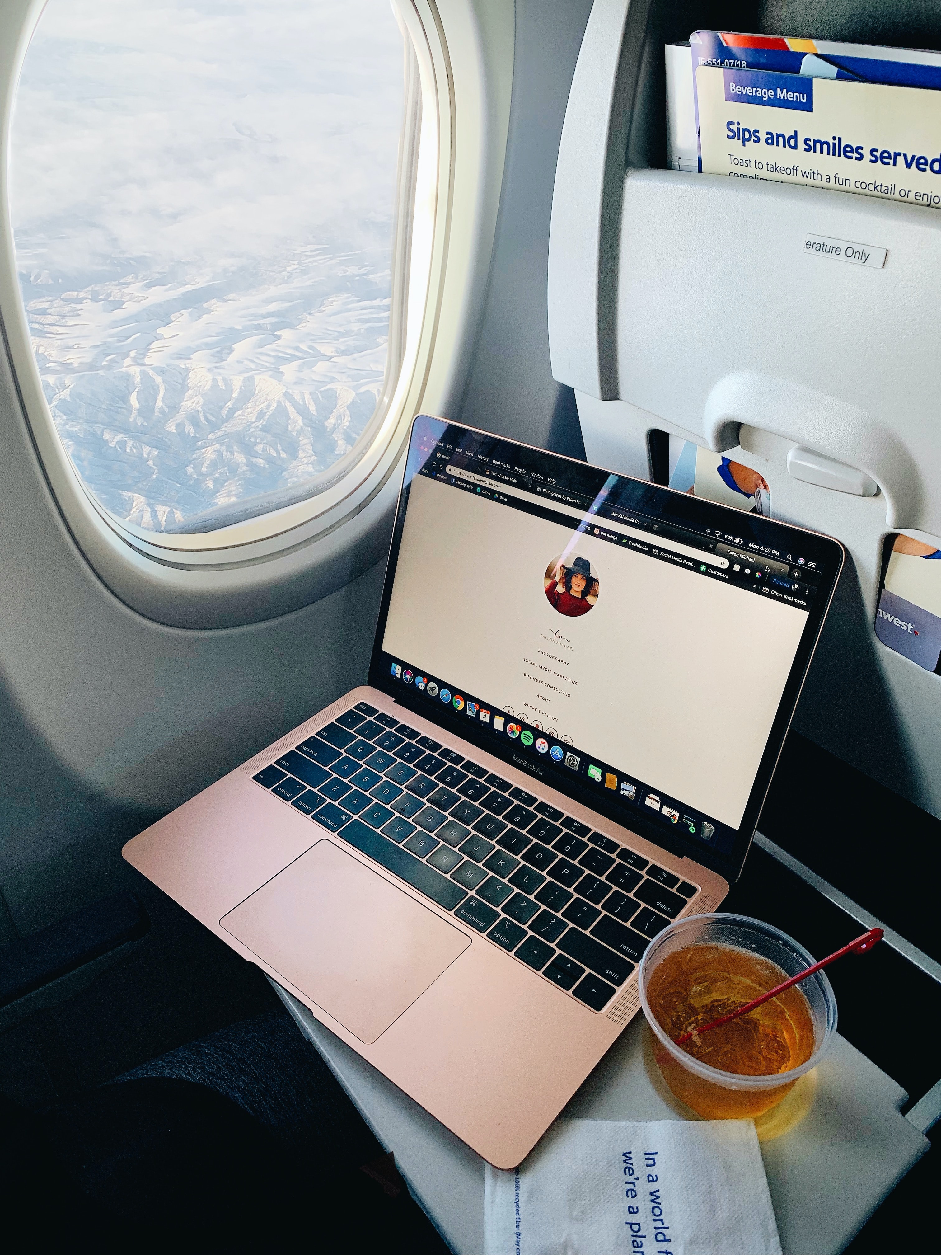 Southwest plane with great leg room. The girl has a laptop set up with a drink and is working on her blog in the flight. 