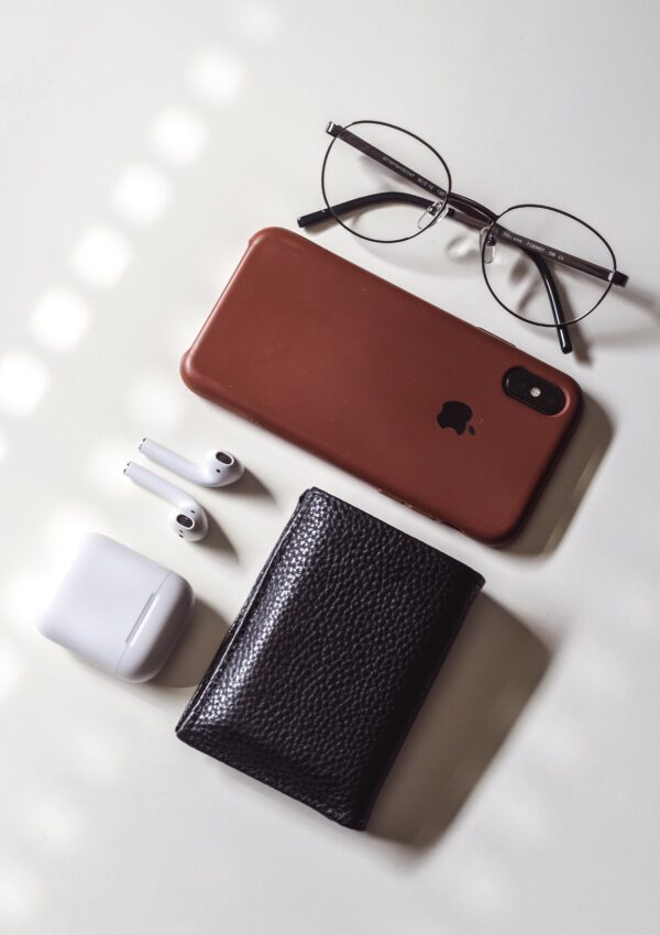 Glasses, an apple phone and headphones and wallet all sitting on a counter for the Discover It cash back review post.