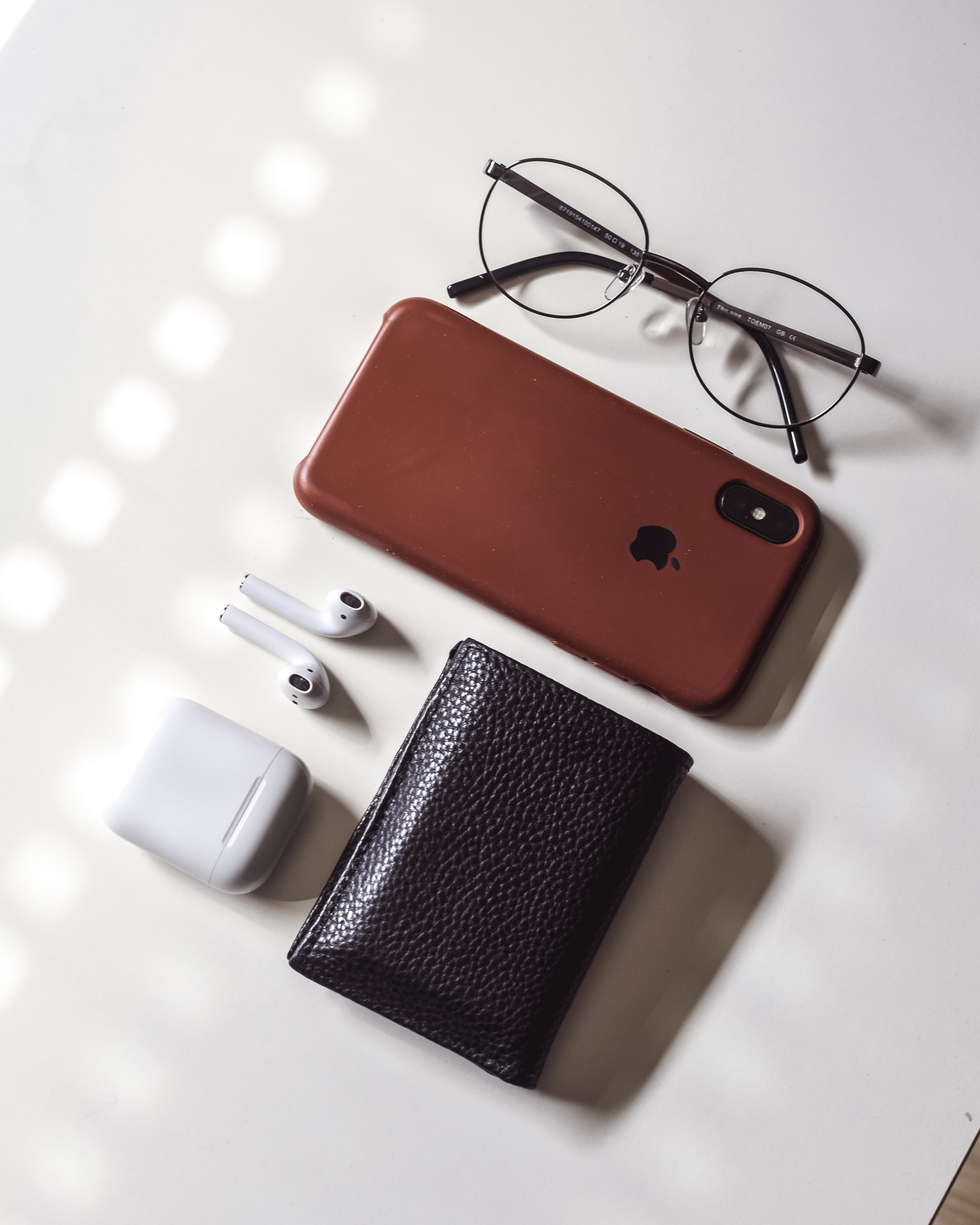 Glasses, an apple phone and headphones and wallet all sitting on a counter for the Discover It cash back review post. 