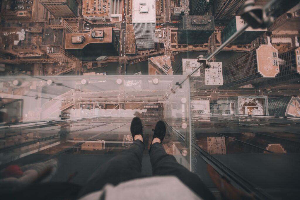 Photo of someone standing on the Chicago Skydeck. Their feet are 1000 feet above the street. 