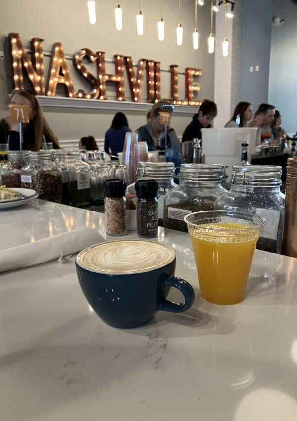 A vanilla latte and fresh squeezed orange juice in front of a sign that says Nashville. A great stop for a weekend in Nashville