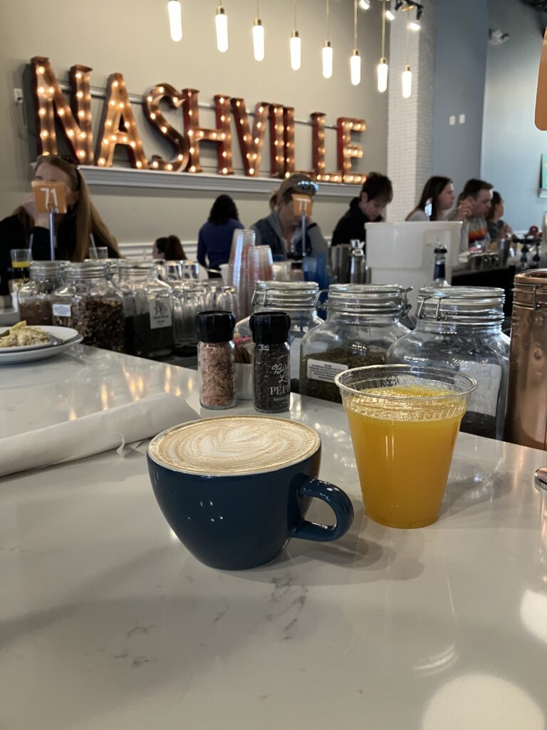 A vanilla latte and fresh squeezed orange juice in front of a sign that says Nashville. A great stop for a weekend in Nashville