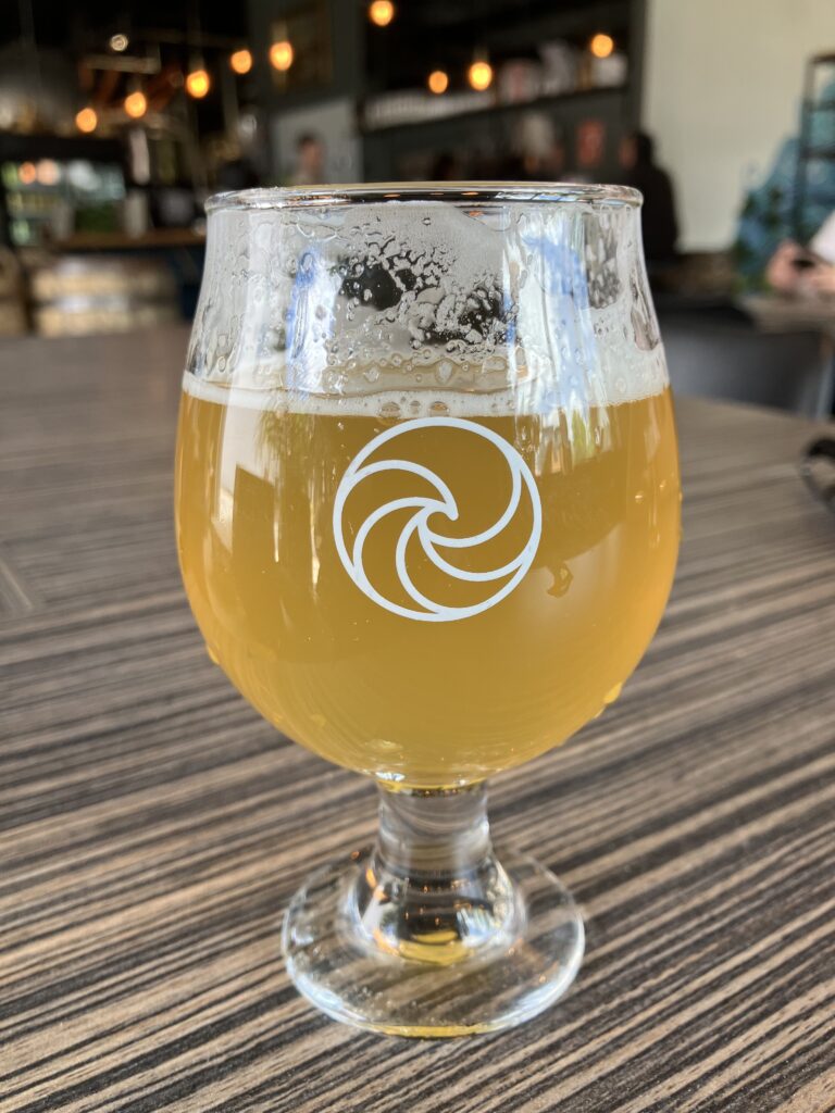 A pint of beer with a swirly water symbol on the glass. A beer from Living Waters Brewery.