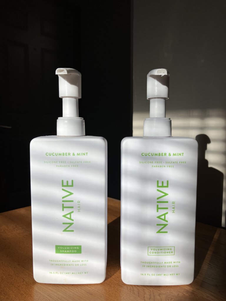 Native Shampoo and Conditioner sitting on a wooden table in the morning light posing for the Native shampoo review.